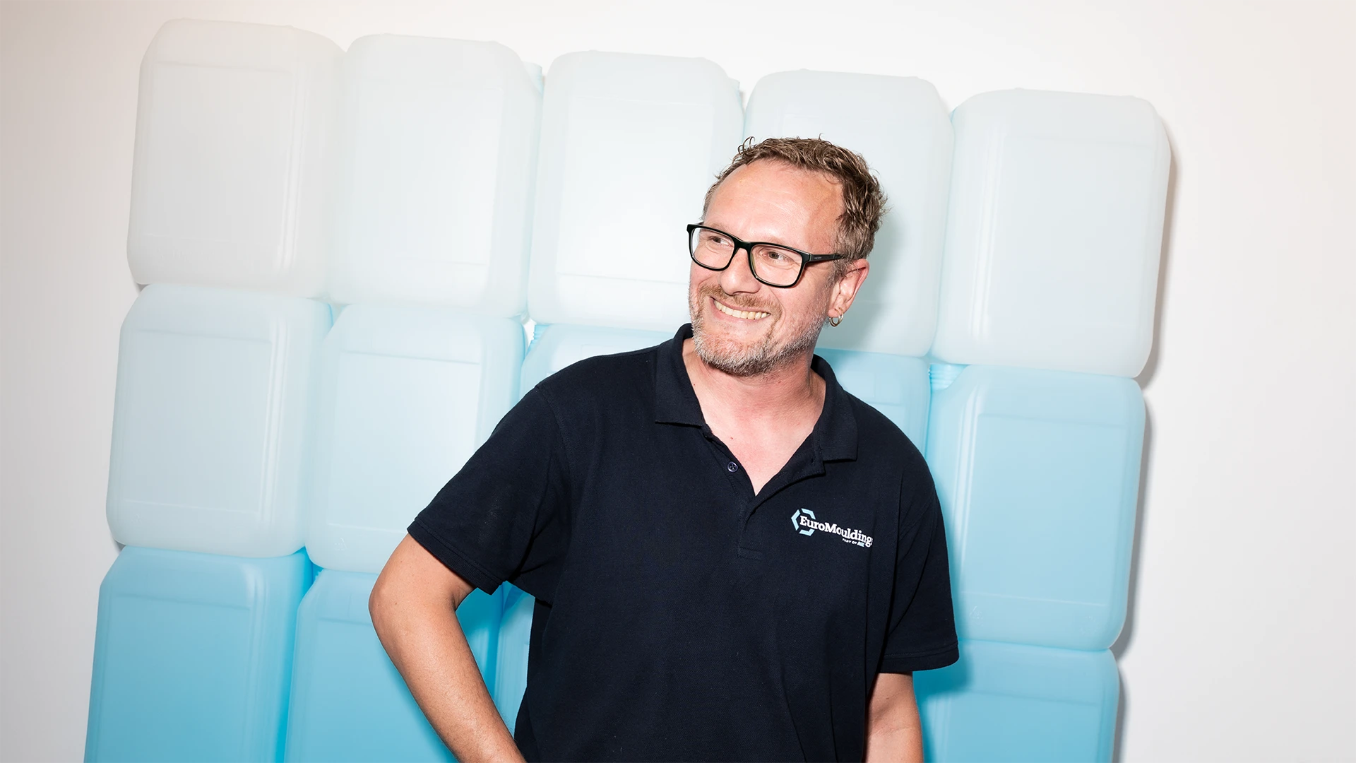 Lachende medewerker in zwart poloshirt tijdens werk bij Euromoldings
